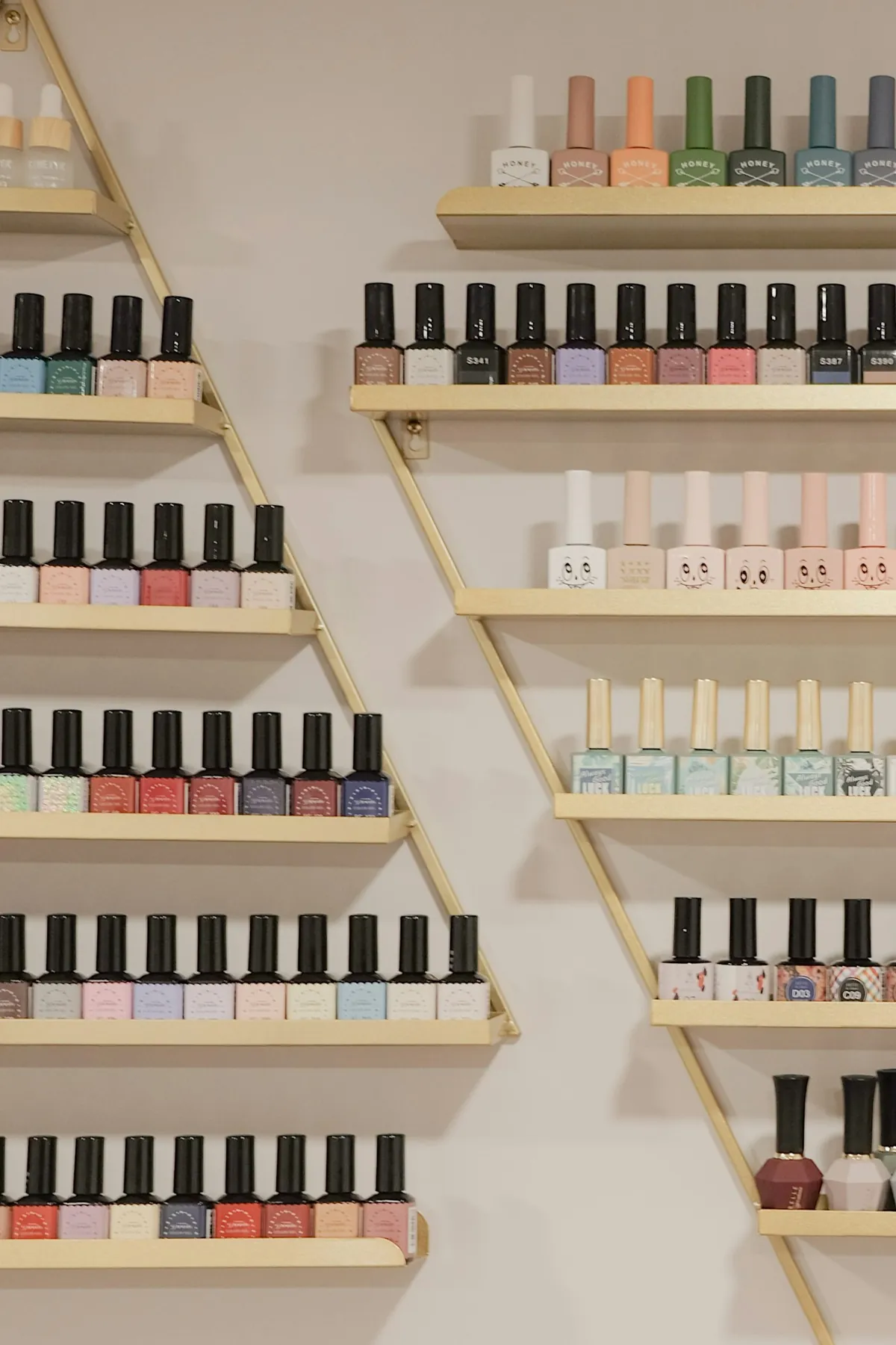 Pared de esmaltes de colores ordenados en estantes dorados