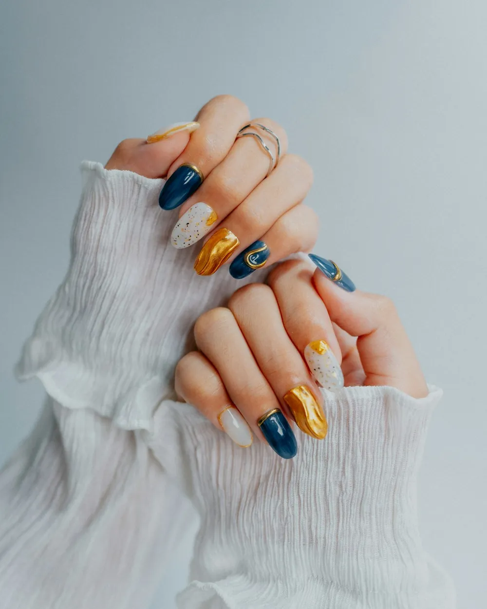 Uñas en azul marino y dorado con detalles brillantes