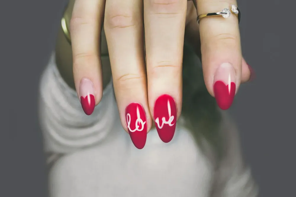 Uñas rojas con la palabra love escrita a mano