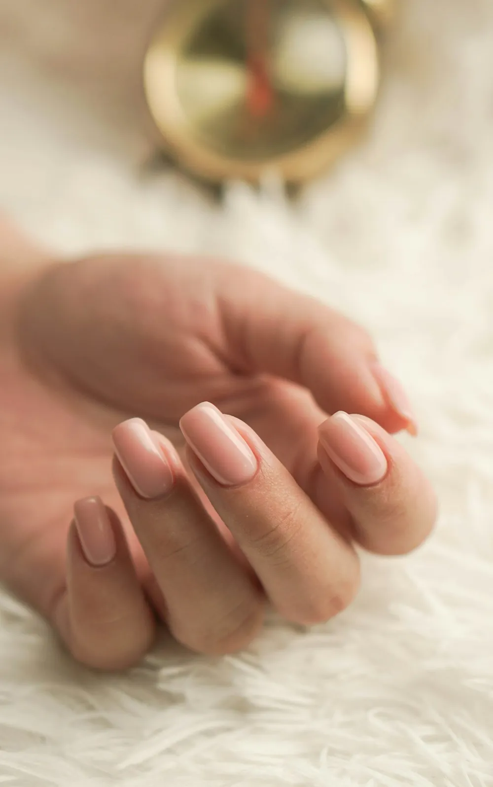 Uñas almendra en tono nude sobre una manta blanca