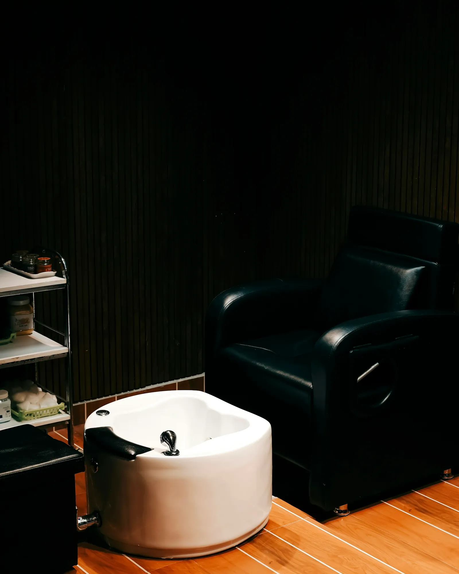 Sillón de pedicura negro con bañera para los pies en una sala tranquila